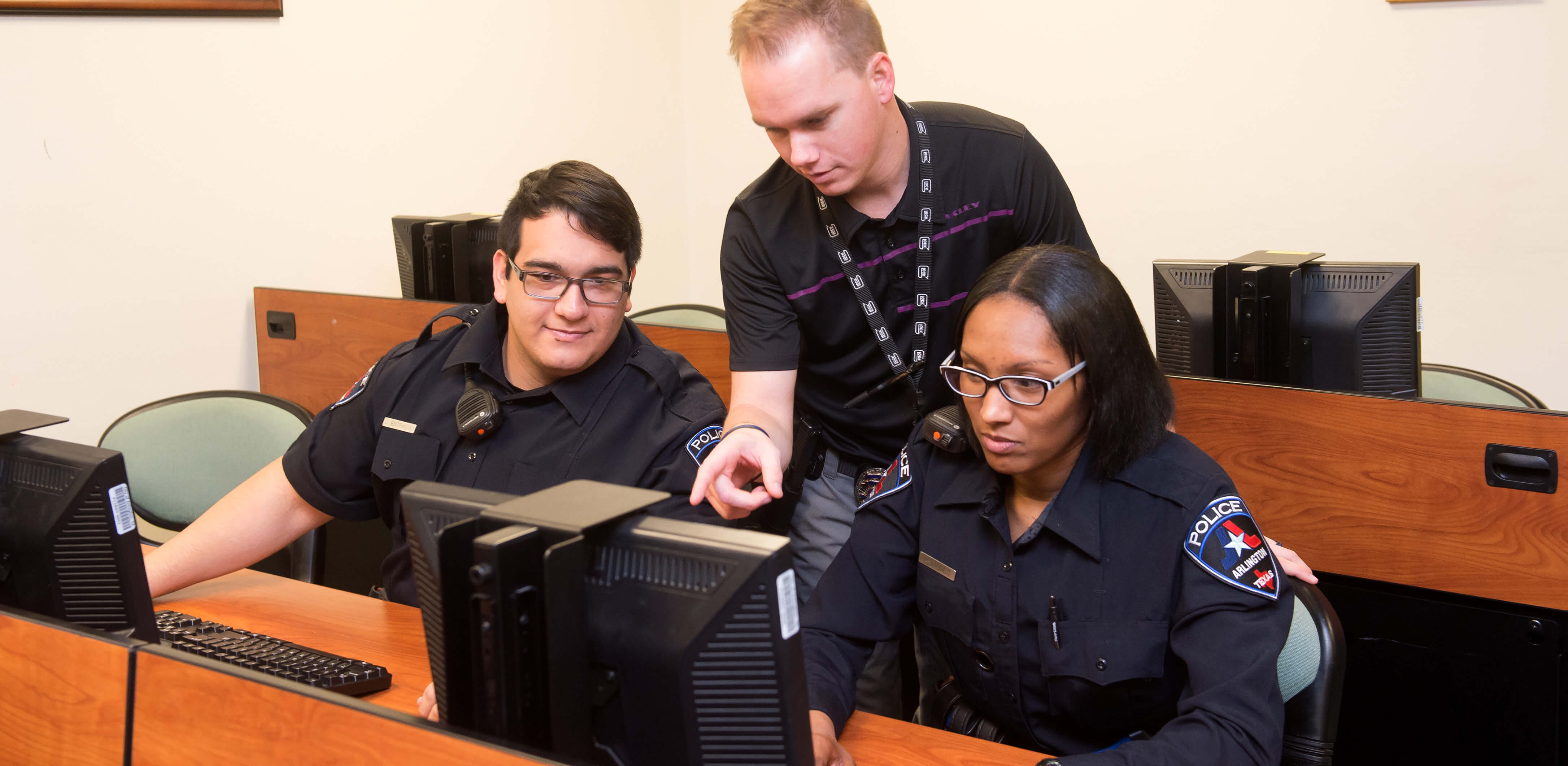 An instructor teaches two trainees on new computer system