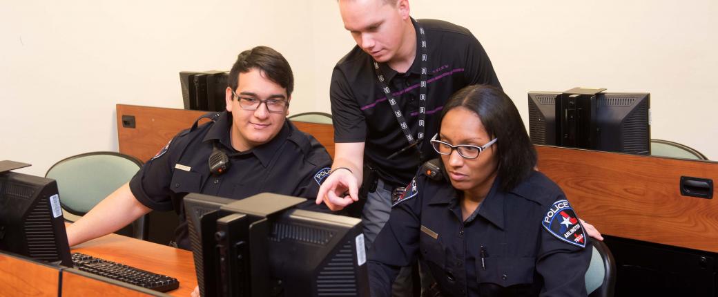 An instructor teaches two trainees on new computer system