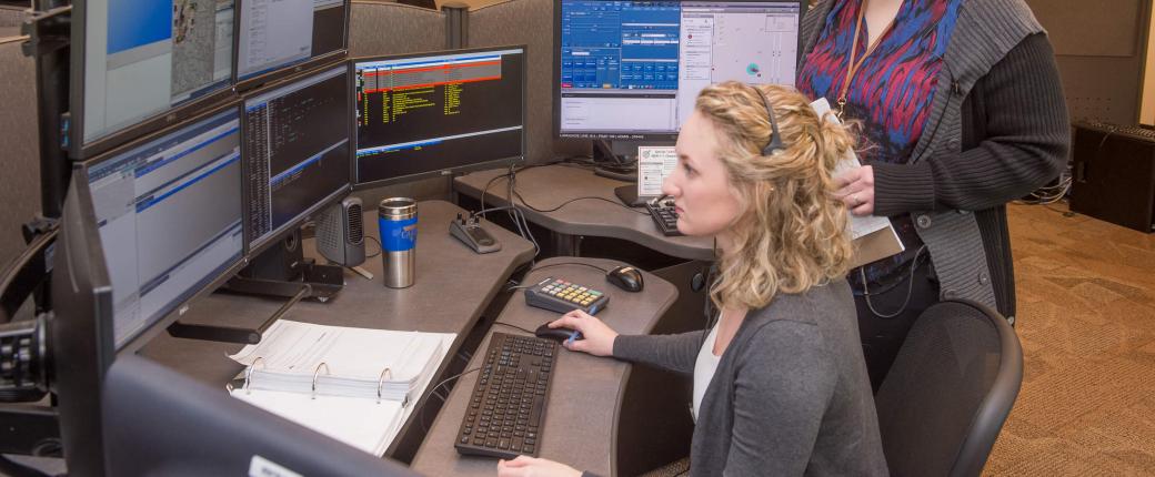 Two employees overlooking dispatch computers in station