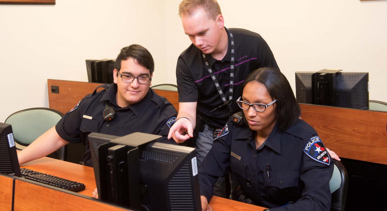 An instructor teaches two trainees on new computer system